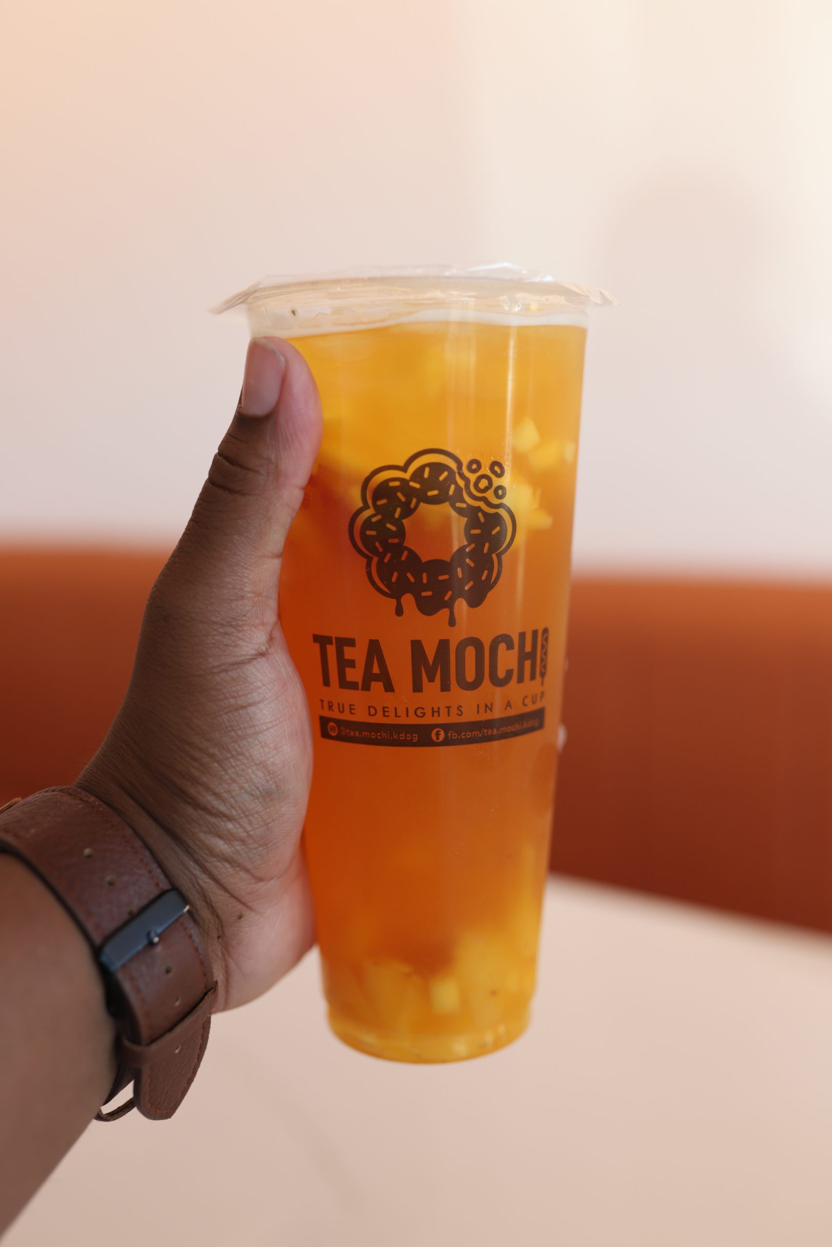 A hand holding a Tea Mochi drink
